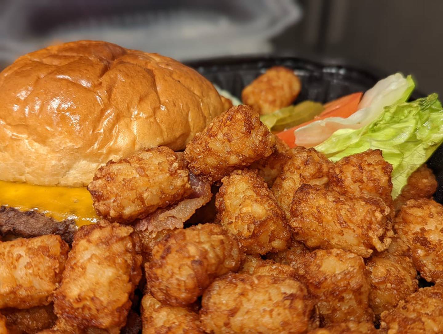 Here is the bacon cheddar burger with tots as served by Skooter's RoadHouse in Shorewood. The veggies were placed to the side so they wouldn’t get warm and soft. The burger was well-cooked and seasoned with plenty of cheese and bacon. The bun was nicely toasted. 
The tots were crunchy and well-seasoned, and there were plenty to eat.