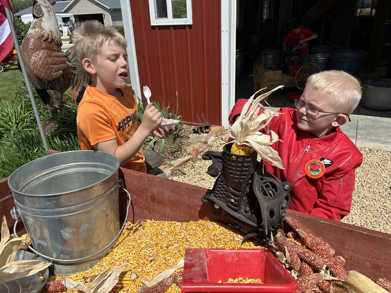 The 16th Annual AJ’s Garden Tractor Jamboree on Saturday, May 17, 2025 included activities for kids. Here, Easton James, 7, of Oregon, (right) runs a hand sheller as Kyler Kitson, 8, of Harvard, eats ice cream as he "supervises".