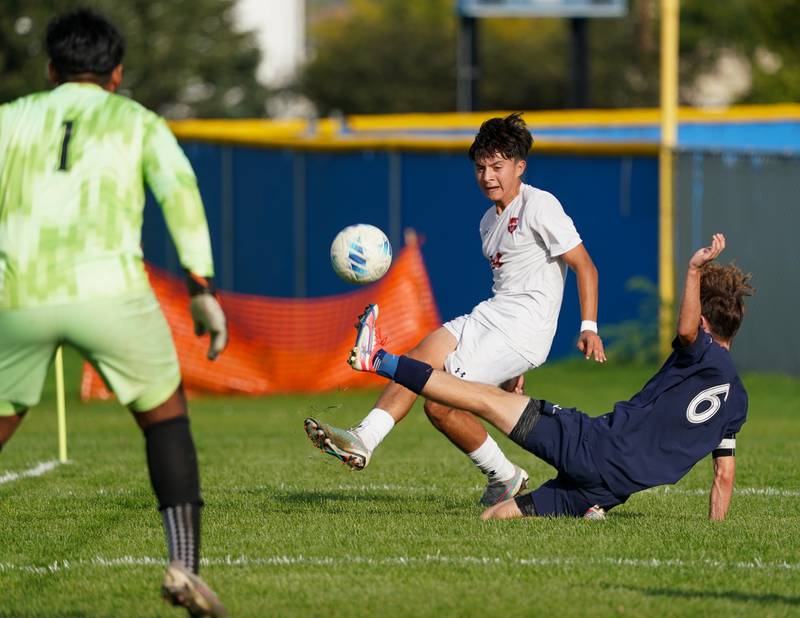 Oswego’s David Castro (14) crosses the ball against Oswego East's Nicholas Smith (6) and Javier Ruiz (1) during a soccer match at Oswego East High School on Tuesday, Sept. 26, 2023.