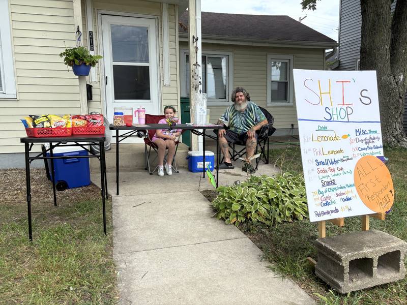 Shiloh Pantoja and her dad sit together at her lemonade stand on Monday, Aug. 11, 2025, as they raise funds to help flood victims in Texas.