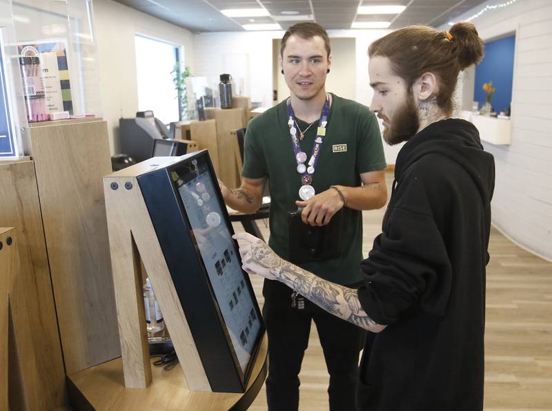 Dakota Tonnberg, left, a patient care specialist at RISE, helps Dylan Scott, of Crystal Lake, shop for marijuana products Thursday, July 14, 2022, at RISE, 270 North Randall Road in Lake in the Hills. Marijuana is set to grow both across the state and in McHenry County. Currently, RISE in Lake in the Hills is the lone dispensary open in the county.