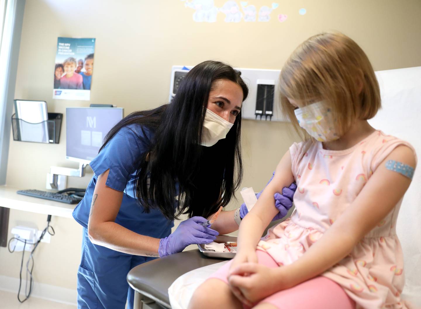 Registered Nurse Samantha Bartulis administers a vaccine to Sofie Reschak, 4, of Crystal Lake at a Northwestern Medicine medical office on Friday, July 22, 2022. Sofie was there for her back-to-school booster shots.