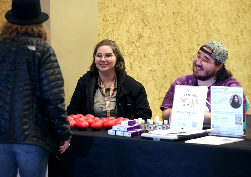 Beth Ganion and Harvey Green, with Safe Passage, greet a visitor Monday, April 7, 2025, during the Safe Passage Take Back the Night and Survivor Speak Out at the Egyptian Theatre in Dekalb. The event is held in conjunction with Sexual Assault Awareness Month.