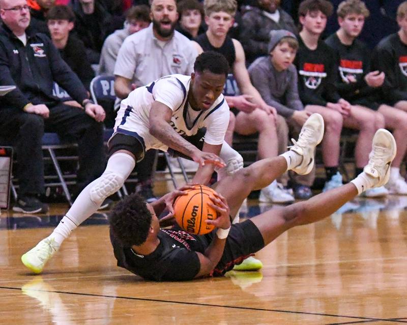 Oswego East's Reggie McWaine, right, and Yorkville's Christian Harrell battle for a loose ball during the game on Friday Feb. 14, 2025, held at Oswego East High School.