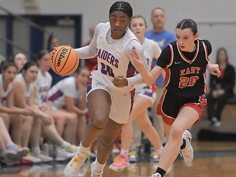 Glenbard South’s Brooklynn Moore brings the ball up court as Glenbard East’s Olivia Nee runs with her in a girls basketball game in Glen Ellyn on Friday, Feb. 7, 2024.