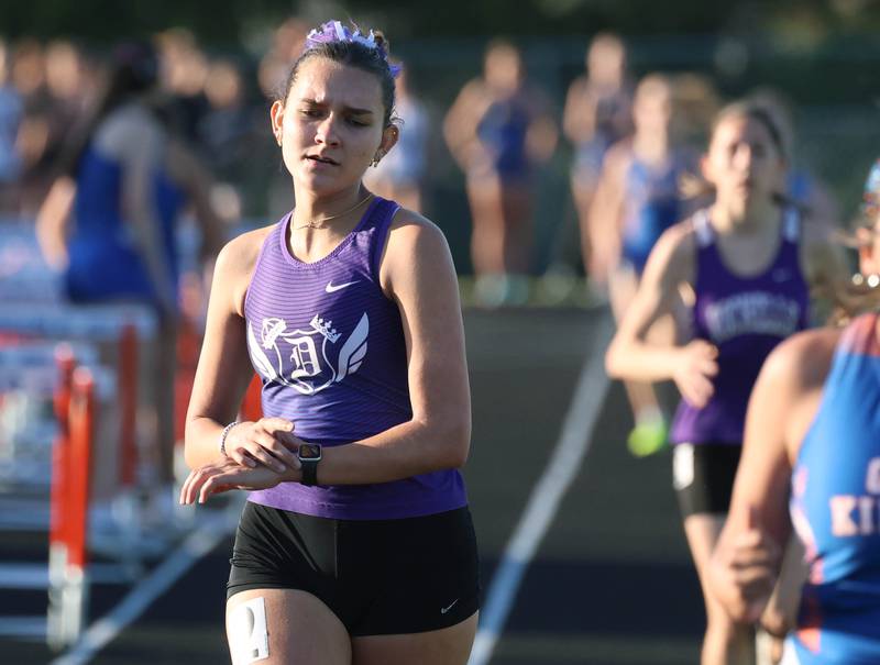 Dixon’s Daniela Lovett checks her watch as she completes a lap in the 3200 meter run Friday, May 15, 2026, during the Class 2A girls track sectional at Genoa-Kingston High School.