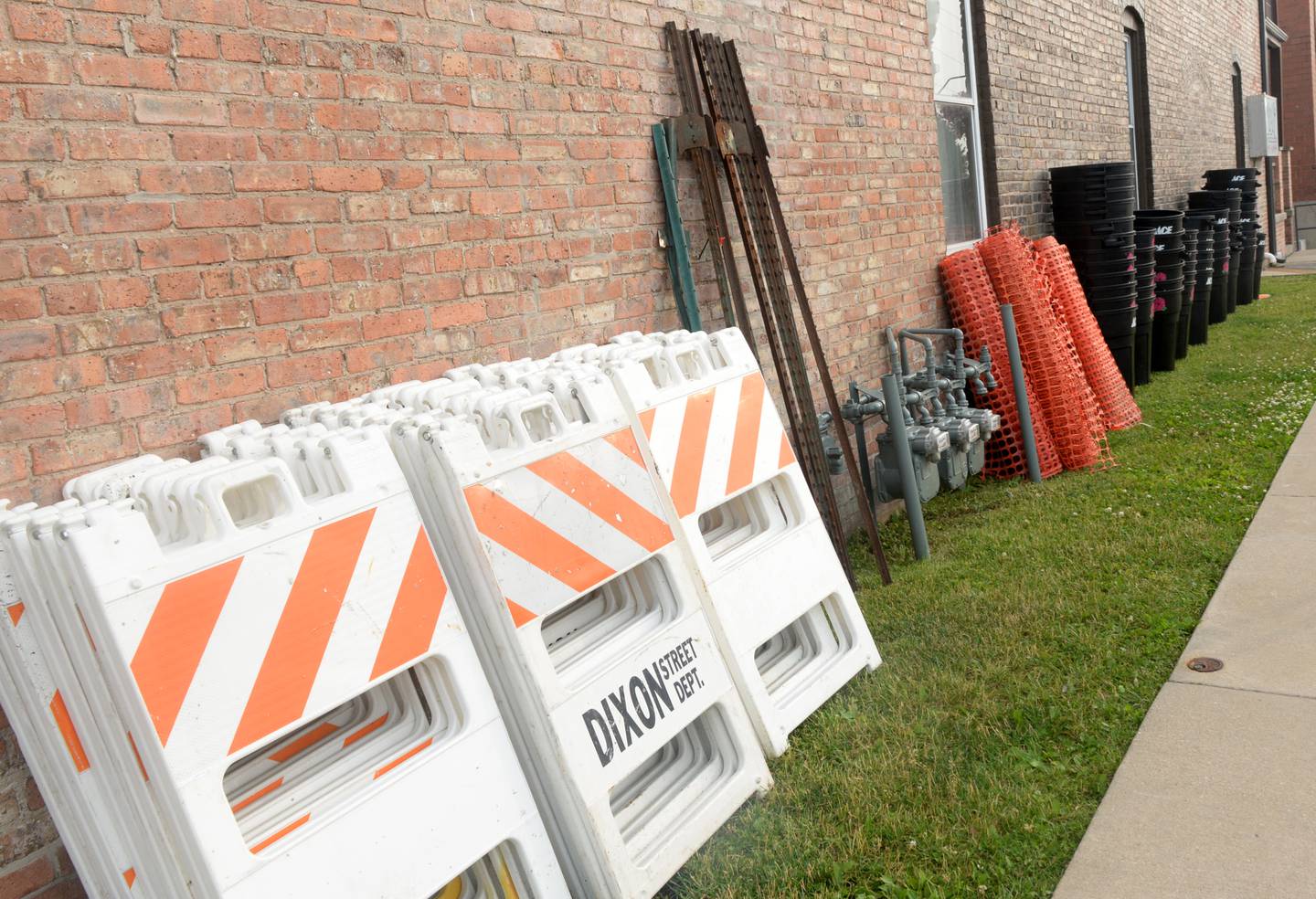Waste barrels and fencing are lined up along a building near the Riverfront in Dixon on Thursday waiting to be deployed for the Petunia Festival.