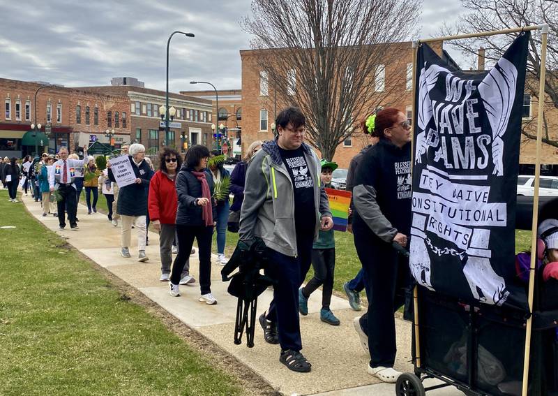 Participants hold signs during a procession at a Palm Sunday Faith Action event on Sunday, March 29, 2026, in front of the DeKalb County Courthouse in Sycamore. Area Christian ministers organized the event to combat the rise of Christian nationalism in the U.S.