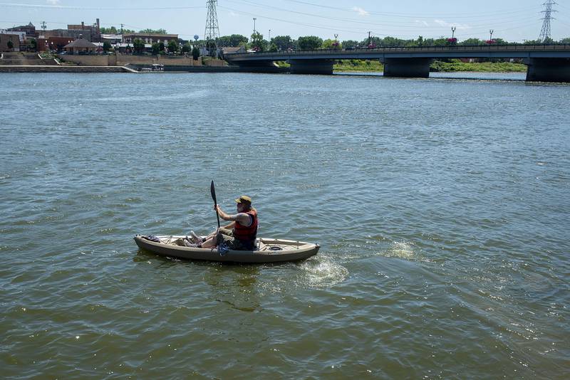 Mark Stach paddles out to the Galena Avenue bridge on July 21 in search of the lost pieces of the collapse Truesdell bridge.