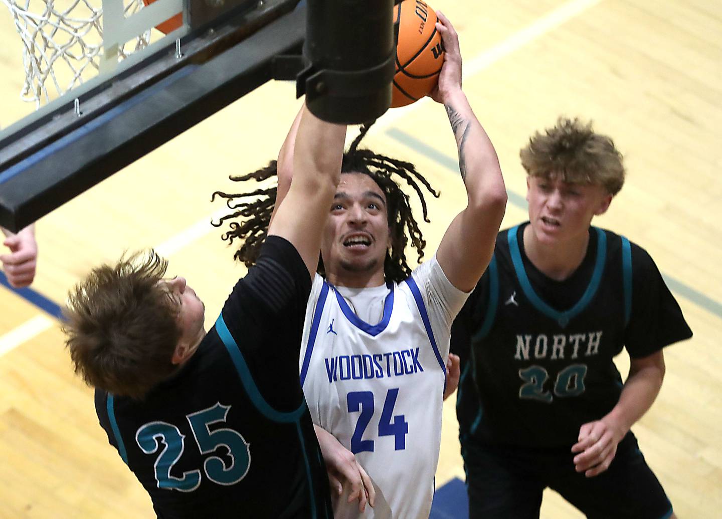 Woodstock's JJ Stokes (center) drives to the basket between Woodstock North's AJ Cohen  (left) and Ethan Richardson (right) during a Kishwaukee River Conference boys basketball game on Wednesday, February. 18, 2026, at Woodstock High School.