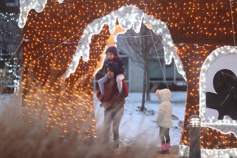 A family walks along the holiday lit park path at New Lenox’s Christmas in the Commons.