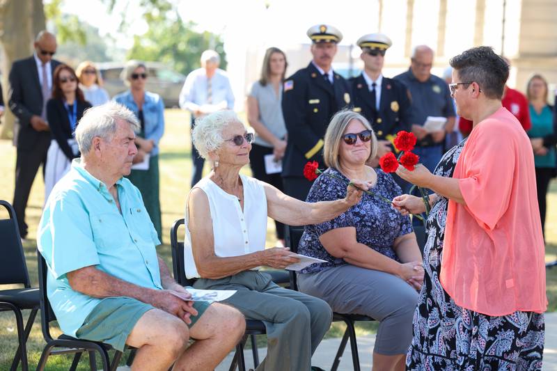 Danielle Dugan, administrative assistant with the Bradley Fire Department, hands a flower to Linda Taylor-Gerretse, former wife of fallen Otto Township firefighter Michael Taylor, alongside her daughter Shawna Taylor, during the 44th Kankakee County Fallen Firefighter Memorial Service on Friday, Oct. 3, 2025.