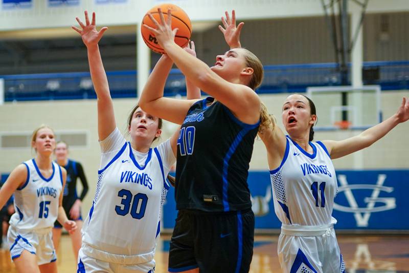 St. Charles North's Elle Fuhr (40) shoots then ball in the post against Geneva’s Keira McCann (30) and Heidi Clesen (11) during a game at Geneva High School on Thursday, Dec. 4, 2025.