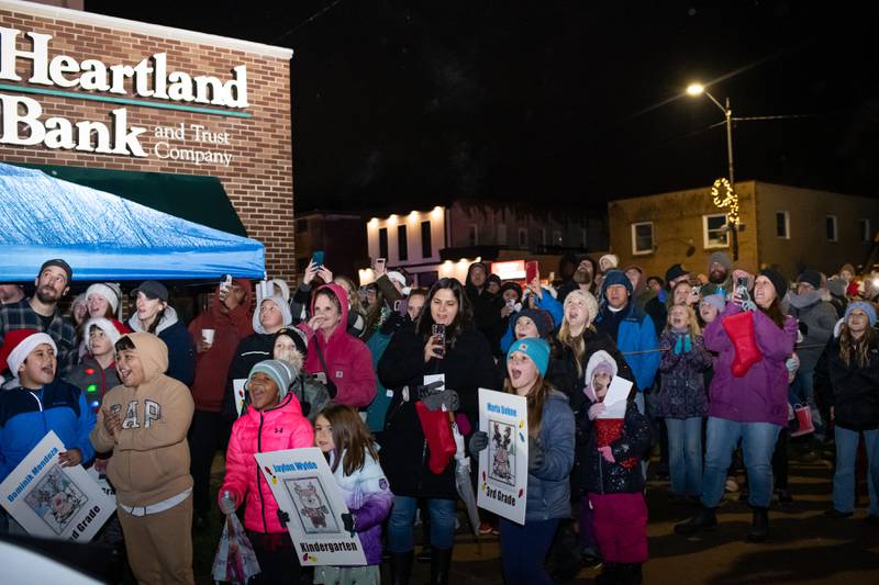 Genoa residents gathered downtown on Friday, Dec. 1, 2023 holding signs to welcome Santa Claus as he visited to help celebrate the season during the Genoa Area Chamber of Commerce's annual Jingle Bell Parade and holiday event.
