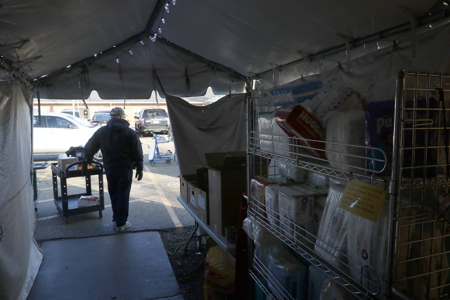 Volunteer Tom Zorn waits in the tent attached to the FISH of McHenry Food Pantry, 3515 N. Richmond Road in Johnsburg, with a cart of food to give to a recipient on Tuesday, Jan. 10, 2023. The pantry, which has changed how it distributes food since the COVID-19 pandemic, is now raising $150,000 to add more storage and a heated garage onto the building.