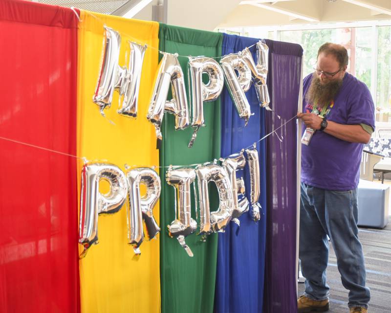 John Wohlers a Waubonsee Community College employee and West Chicago resident hangs balloons to the photo background before the start of the pride party held at Waubonsee Community College in Plano on June 29, 2023.