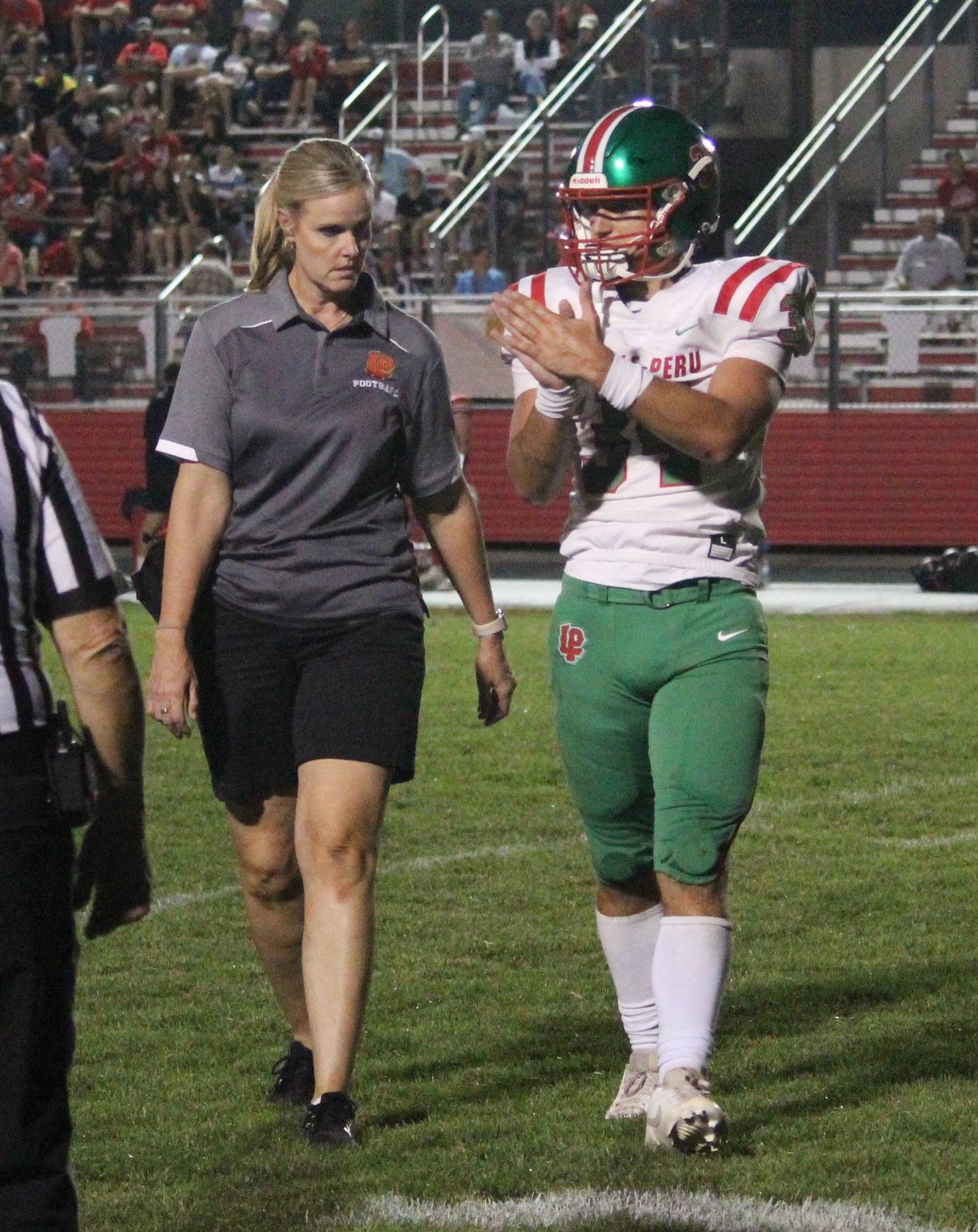 La Salle-Peru athletic trainer Gina Martin (left) walks off the field with a player.