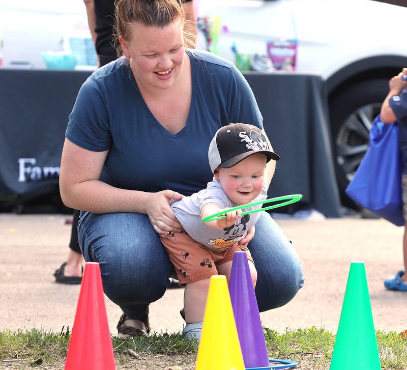 Brixton Kittleson, 1, from DeKalb, gets some help from his mom Kelli playing ringtoss at the DeKalb Park District booth Thursday, July 21, 2022, during the DeKalb Chamber of Commerce Family Fun Fest at Hopkins Park in DeKalb.