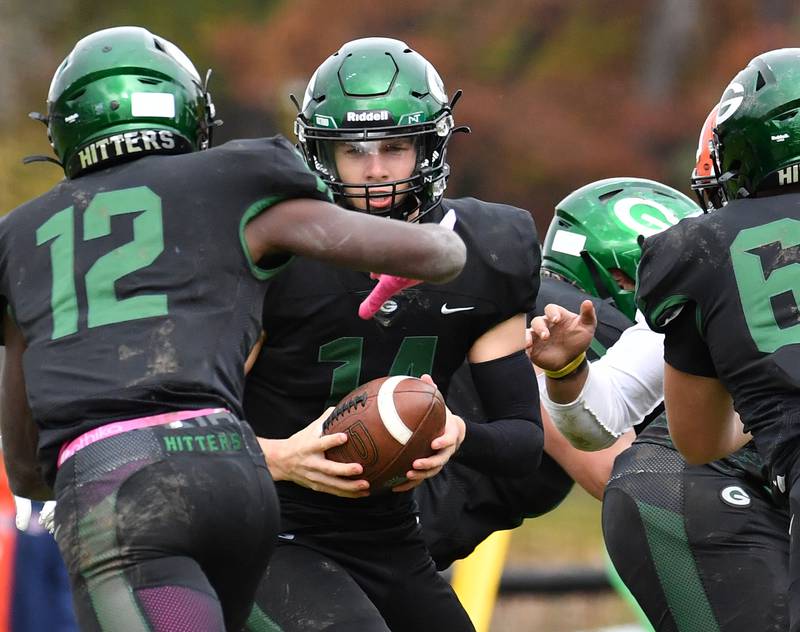 Glenbard West quarterback Charlie Cline (14) hands the ball off to Teyion Oriental (12) during an IHSA Class 8A playoff game against Naperville North on Oct. 28, 2023 at Glenbard West High School in Glen Ellyn.