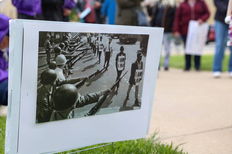 A photograph of the 1968 Memphis sanitation strike, where over 1,300 African-American workers protested against dangerous working conditions, low wages, and a lack of dignity, is displayed at the May Day Strong rally at the Kankakee County Courthouse on May 1, 2026, as part of a national day of action.