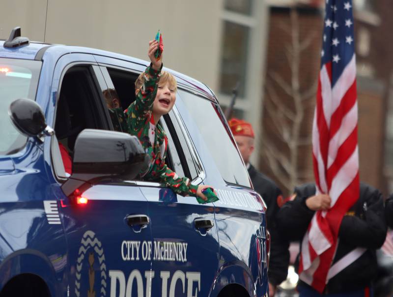 A youngster offers candy from a police cruiser during the Toys for Tots Parade on Sunday, Nov. 24, 2024, in downtown McHenry.