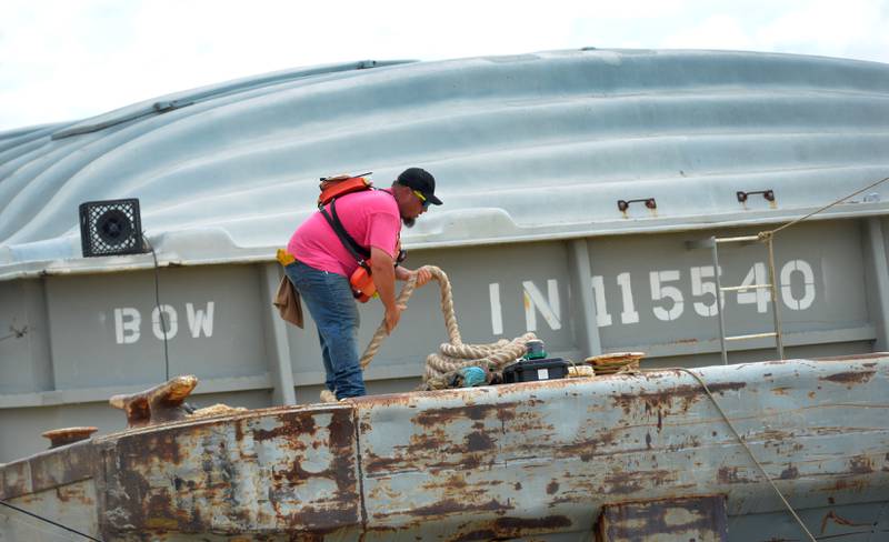 A worker wrangles a guide rope on barges as they pass through the lock at Lock & Dam 13 headed north on the Mississippi River on Sunday, July 6, 2025.