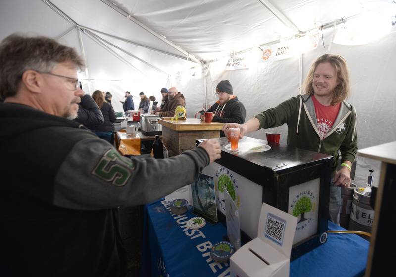 Brian Mejerich of McHenry receives an Elmhurst Brew Company beer from Cam Horn during the Winter Beer Festival held in Westmont Saturday Feb 18, 2023.