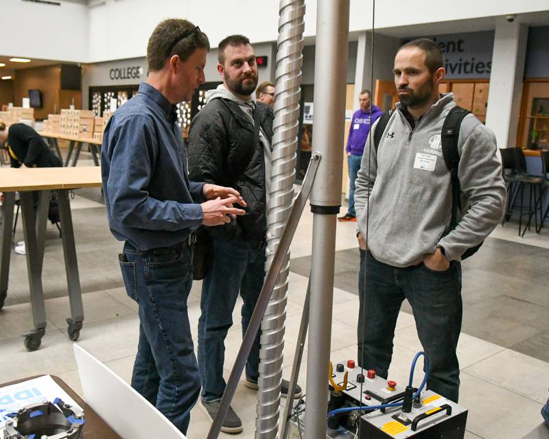 Kyle Cook, right, and Adam Wason, Lockport science teachers talk with Jay Johnson from Ice Drilling Project about one of the drills they use to extract ice from the earth during The Climate of Hope Conference 2024, at Downers Grove North on Friday March 1, 2024.