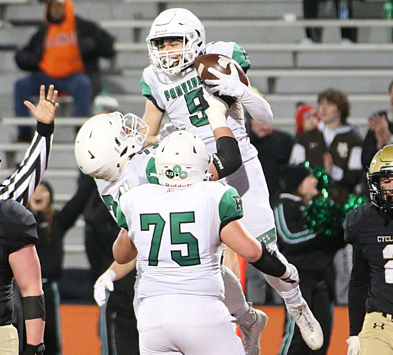 Providence Catholic's Cameron Fultz (9) celebrates with teammates James Barry (73) and Zach Hesselmann (75) after scoring a touchdown against Sacred Heart-Griffin in the Class 4A state title on Friday, Nov. 25, 2022 at Memorial Stadium in Champaign.