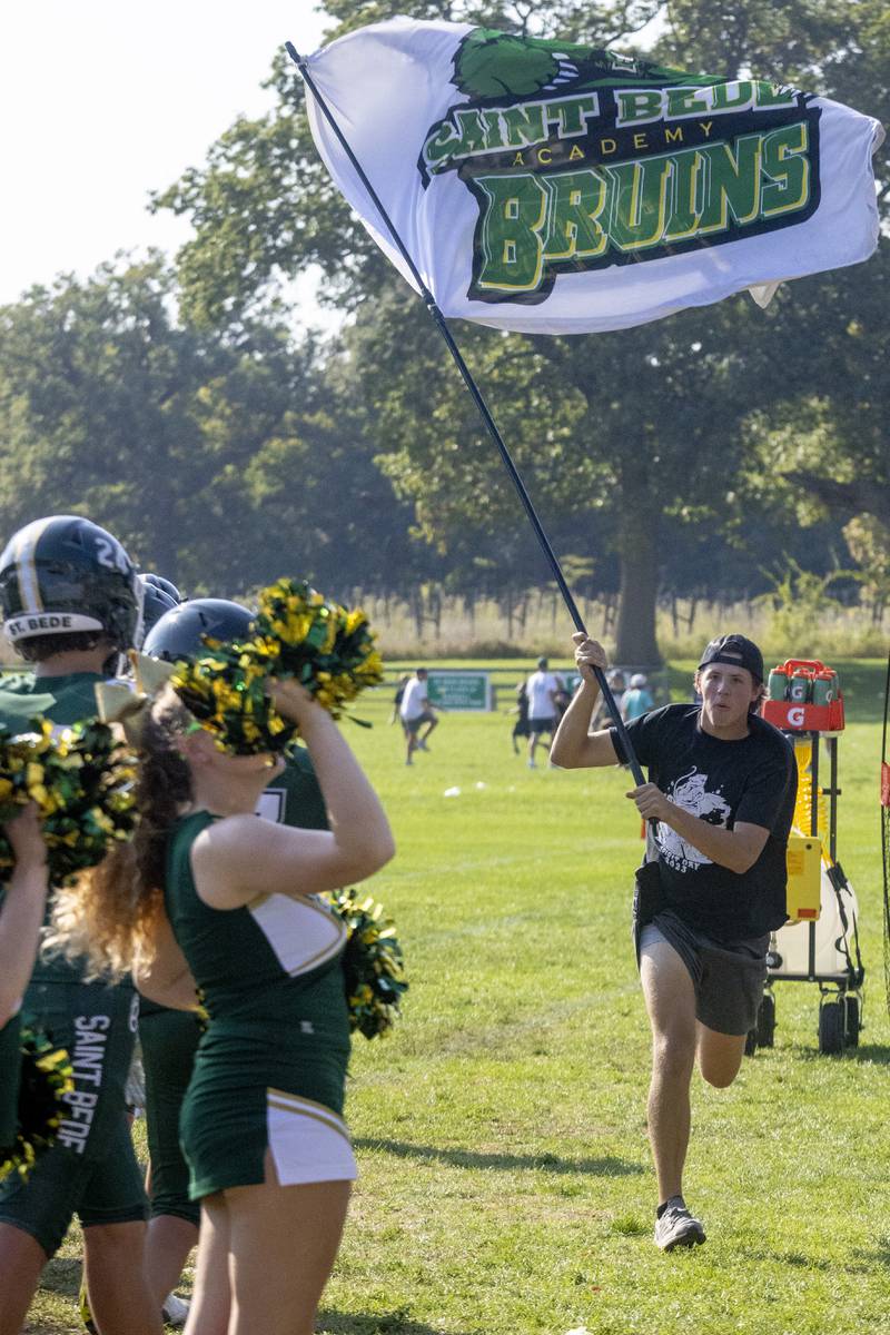 A St. Bede Academy student runs the team flag down the sidelines in celebration of Max Bray's touchdown on September 30, 2023.