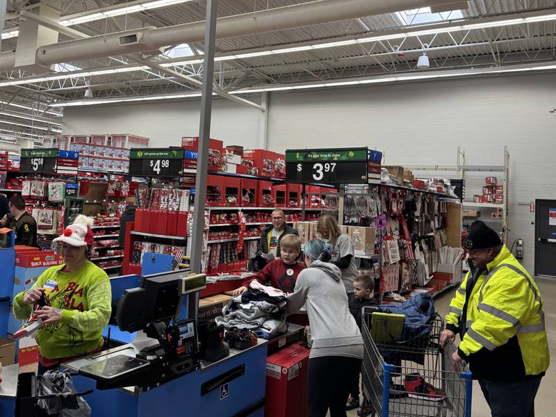 Walmart employees help the kids shopping with local first responders check out after picking out their items.