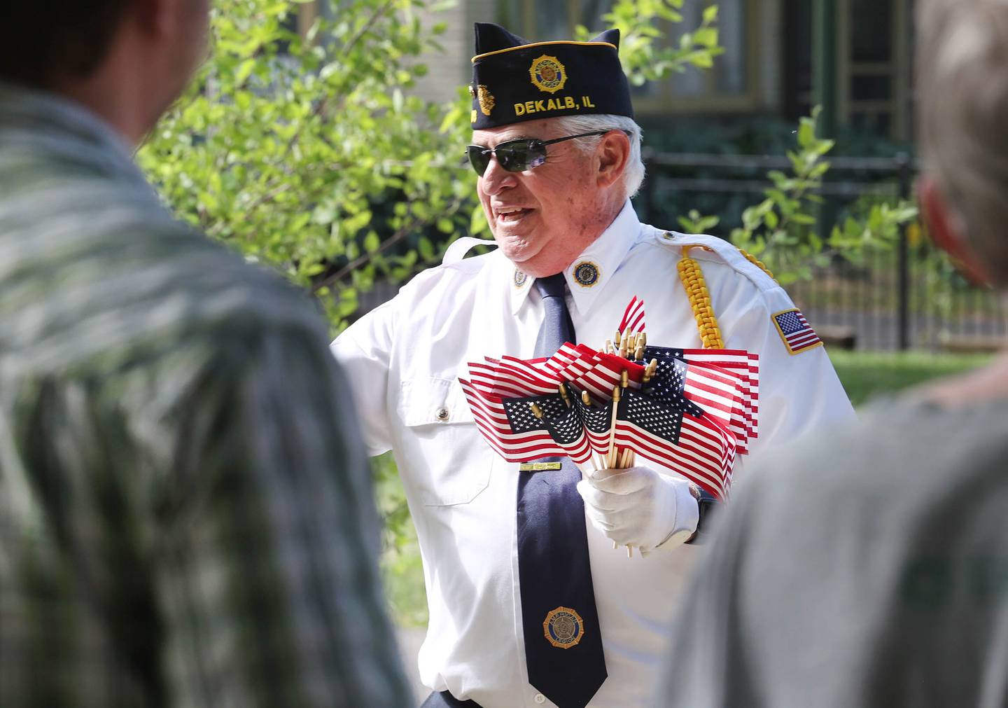 A member of the DeKalb American Legion Post 66 hands out flags Monday, May 29, 2023, during the DeKalb Memorial Day parade.