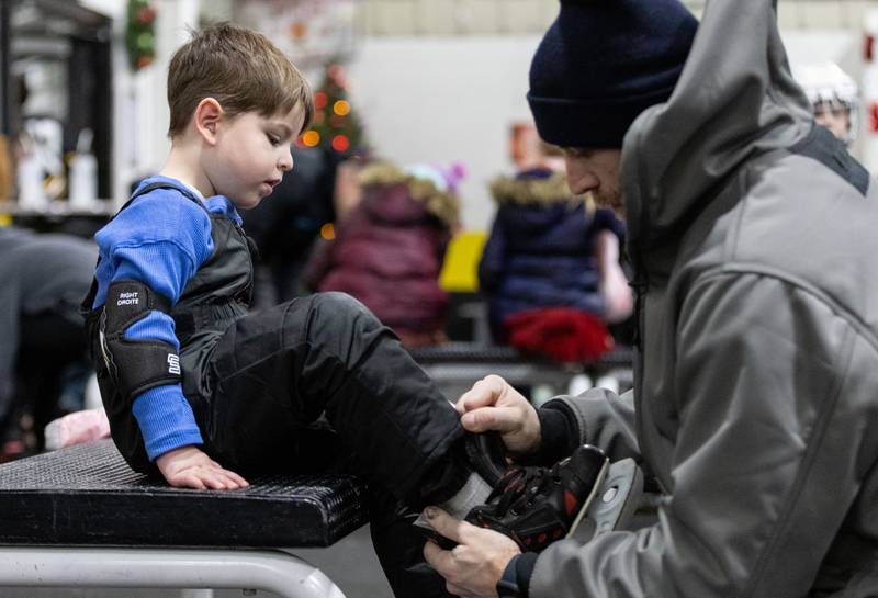 Jack Brown of Lake Barrington helps his son James Brown, 3, with his skates before they participated in an open skate at Crystal Ice House in Crystal Lake on Friday, Jan. 3, 2025.