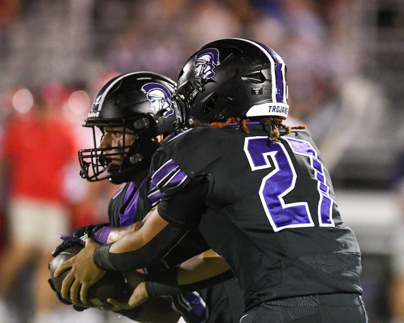 Downers Grove North's Kevin Jay Jr. (27) hands the ball off to teammate Downers Grove North's Oliver Thulin (10) during the game on Friday Sept. 12, 2025, while taking on Hinsdale Central held at Downers Grove North.