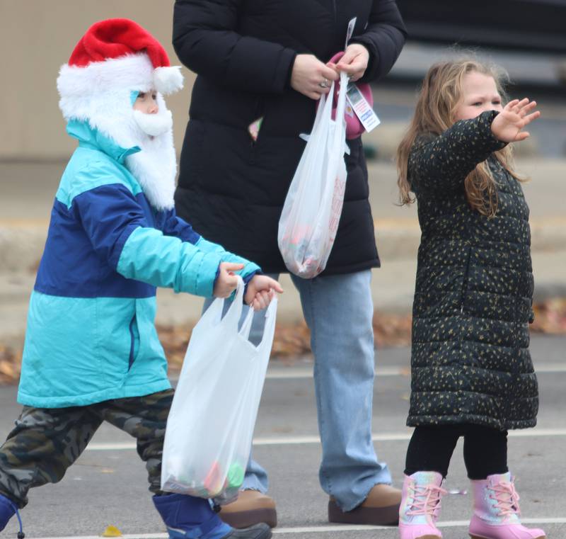Russell Piper, 6, left, and his sister Emeigh, 4, of McHenry, wave for candy during the Toys for Tots Parade on Sunday, Nov. 24, 2024, in downtown McHenry.