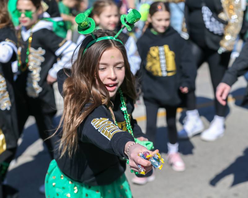 A cheerleader for the Lemont Hornets flag football team hands out candy in the Lemont St. Pat's Day Parade on Saturday, March 8, 2025  in Lemont.