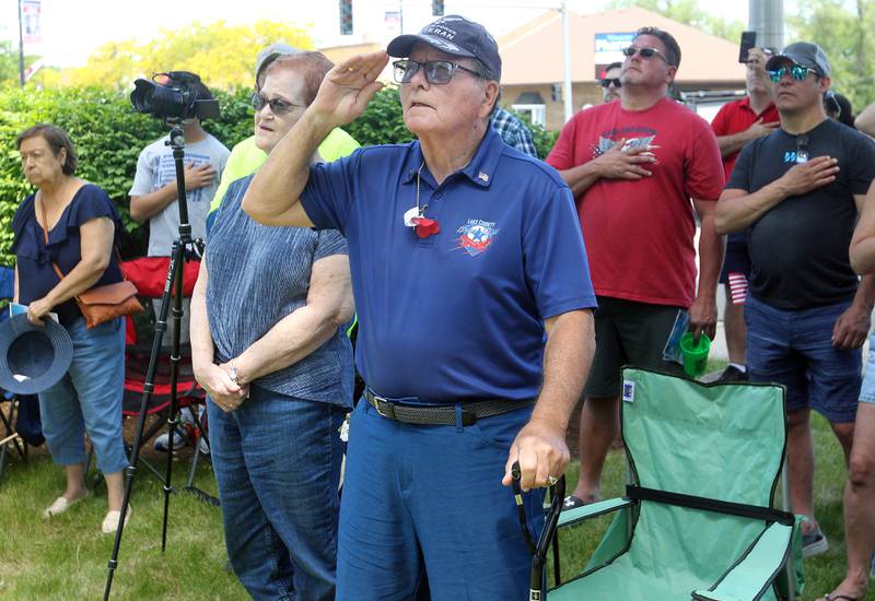 Claudia Piemontese, of Mundelein, stands next to her husband, Lawrence "Pie", a U.S. Air Force veteran, as he salutes during the Wauconda Memorial Day Ceremony on Monday, May 29, 2023, at Memorial Park.