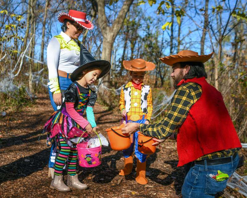 Family members Matteo, 7, Zoe, 5, receive candy as their mom Alda Kerxhalli looks on from a sheriff character on Saturday Oct. 26, 2024, during the Boo Bash trail event held at Ackerman Park in Glen Ellyn.