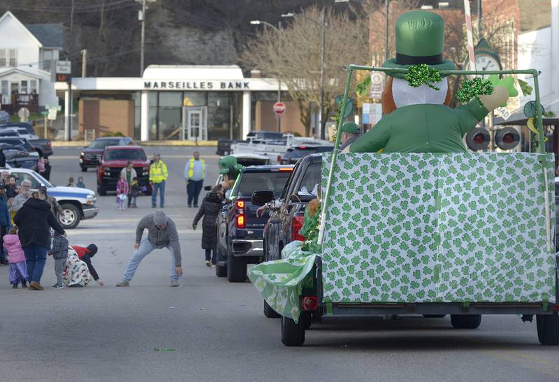Those attending the St Patrick's Day Parade in Marseilles Saturday pick up the candied treats tossed their way along Main St .