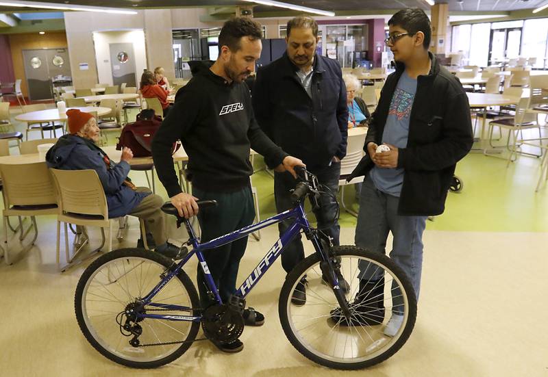 Josh Davis, of Spec, talks with Riyaz Khan and Mohammed Danish after Davis repaired their bicycle during a Repair Fair on Tuesday, April 15, 2025, at McHenry County College.