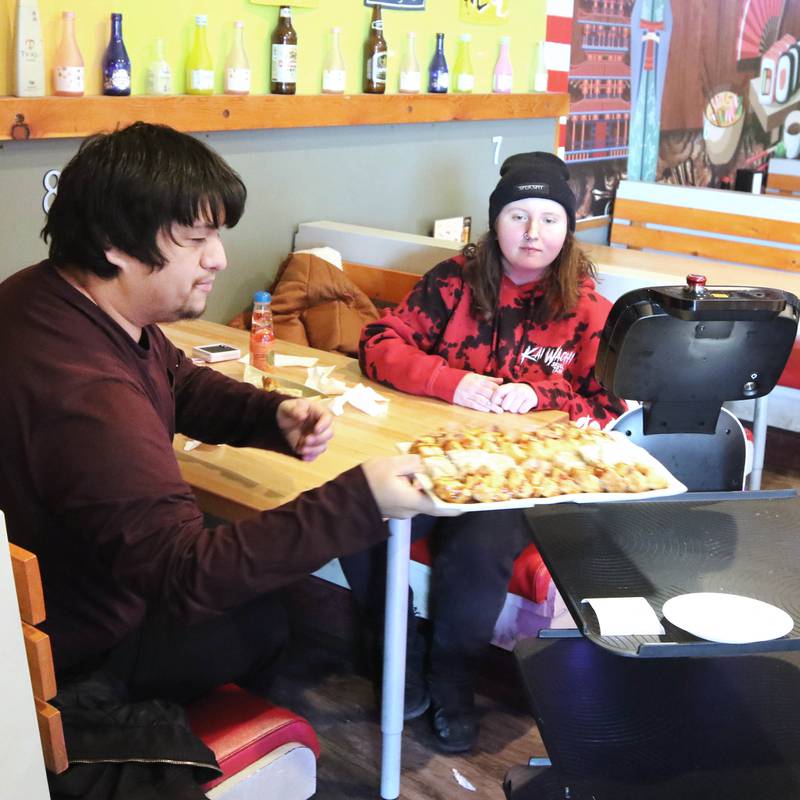 The robot waiter named Mushroom at Fushi Yami hibachi and sushi restaurant in DeKalb delivers an order Friday, Jan. 19, 2024, to David Salgado, from Chicago, and Rachael Iturbide, from Rochelle.