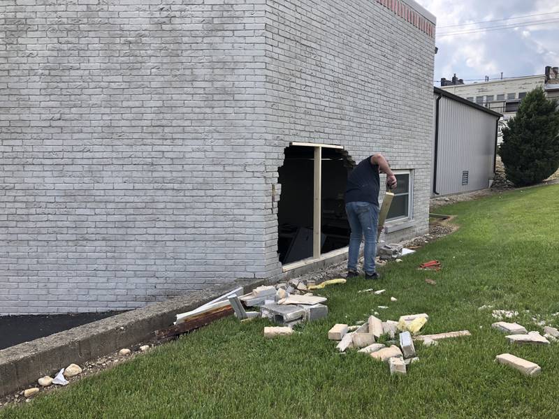 A man clears debris behind Ormsby Motors in Crystal Lake on May 16, 2024, after a car struck the building.