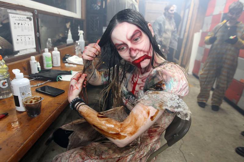 Cat Turowski, of Memphis, Tenn., puts hair protein on her hair and body as she gets into character before visitors arrive at the Realm of Terror Haunted House in Round Lake Beach. Turowski has been a performer at the haunted house for 15 years