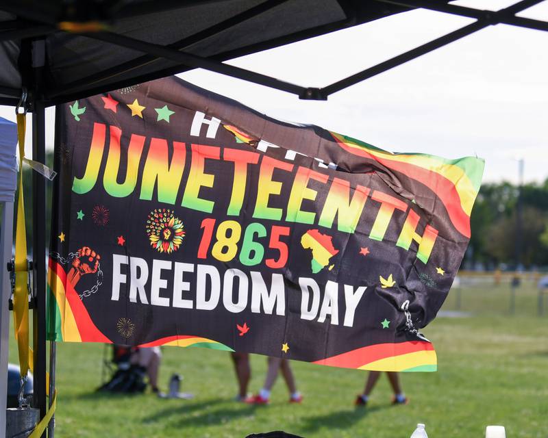 A Happy Juneteenth 1865 Freedom Day flag whips in the wind on Saturday June 15, 2024, during the Juneteenth celebration held at Emily G. Johns School in Plano.