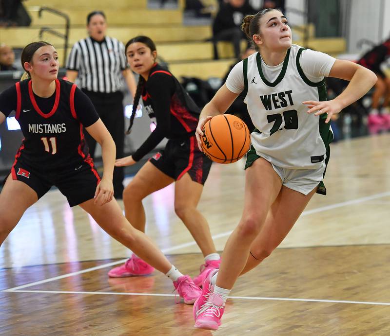Glenbard West’s Ellie Noble (right) drives for a layup past Mundelein’s Casey Vyverman (11) and Gabby MacApinlac during a Grow the Game Showcase game on January 2, 2026 at Glenbard West High School in Glen Ellyn.