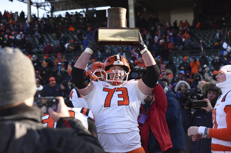 Illinois' Josh Gesky (73) holds up the Land of Lincoln trophy after defeating Northwestern in an NCAA college football game at Wrigley Field on Saturday, Nov. 30, 2024, in Chicago. (AP Photo/Paul Beaty)