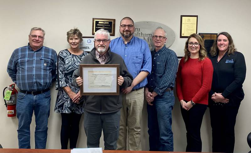 (Left to right) Tom Bruch, Manager Lori Dippel, Board President Frank McConville, Keith King, Gary Small, Angie Dallam and Office Assistant Margaret Leonard show off Peru Waltham's certificate of achievement.