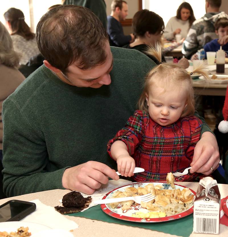 Chris Davisson of Elburn, helps daughter Willow eat breakfast at Breakfast with Santa in Elburn on Sunday, Dec. 4, 2022.