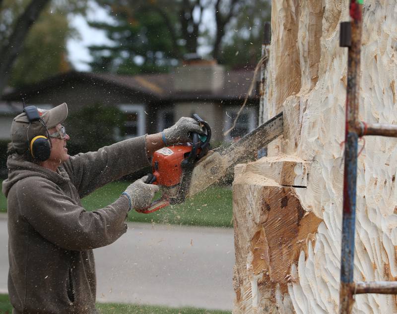 Bud Hainzinger of Morris carves a cross in a tree stump at St. Johns Lutheran Church on Friday, Nov. 3, 2023 in Peru. The family of Don and Ruth Johnson donated the cost of the tree carving in memory of their parents.