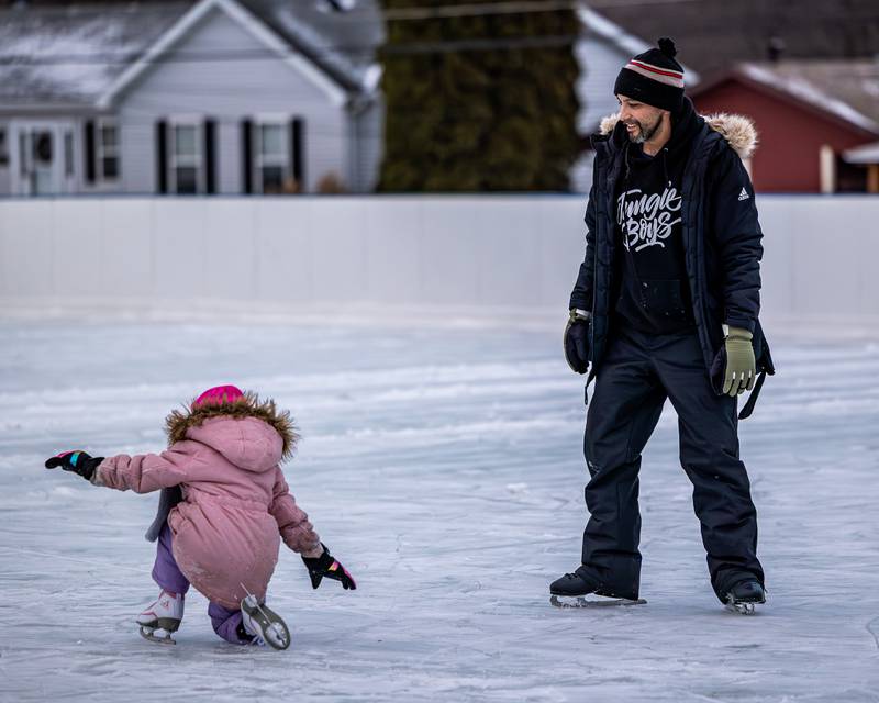 Amilena Policky falls whilst skating and is watched by father Richie Policky at Schweickert Arena's Ice Rink on Tuesday, December 30, 2025, at Washington Park in Peru.